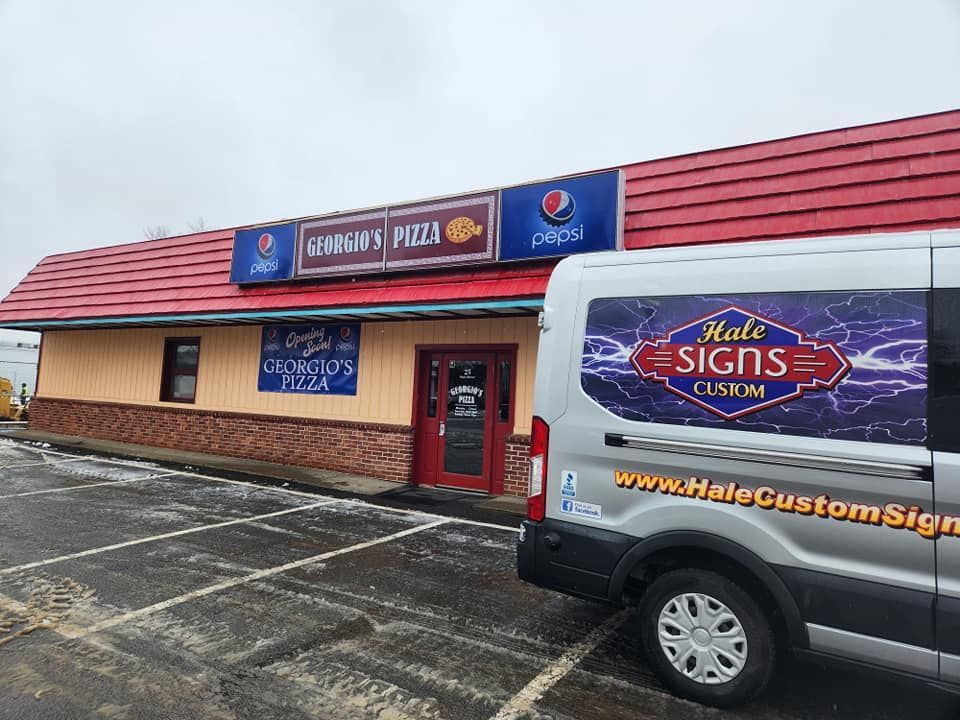 A pizza restaurant, Korner's Pizza, with a red roof and a van from Halo Custom Signs parked in front.