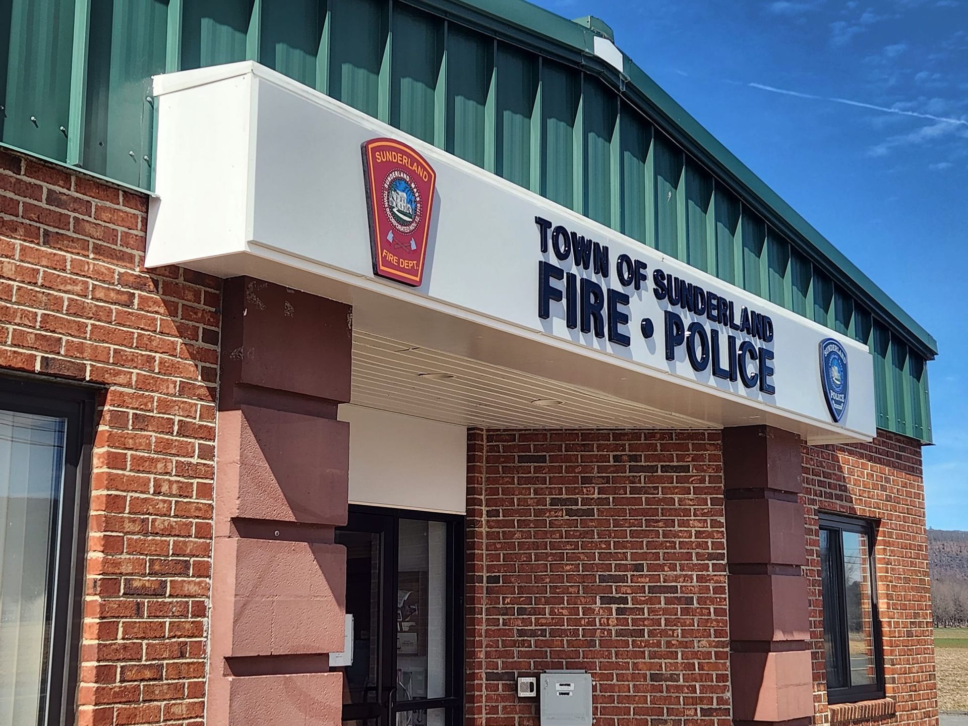 Brick building: Town of Sunderland Fire & Police station with sign and emblems.