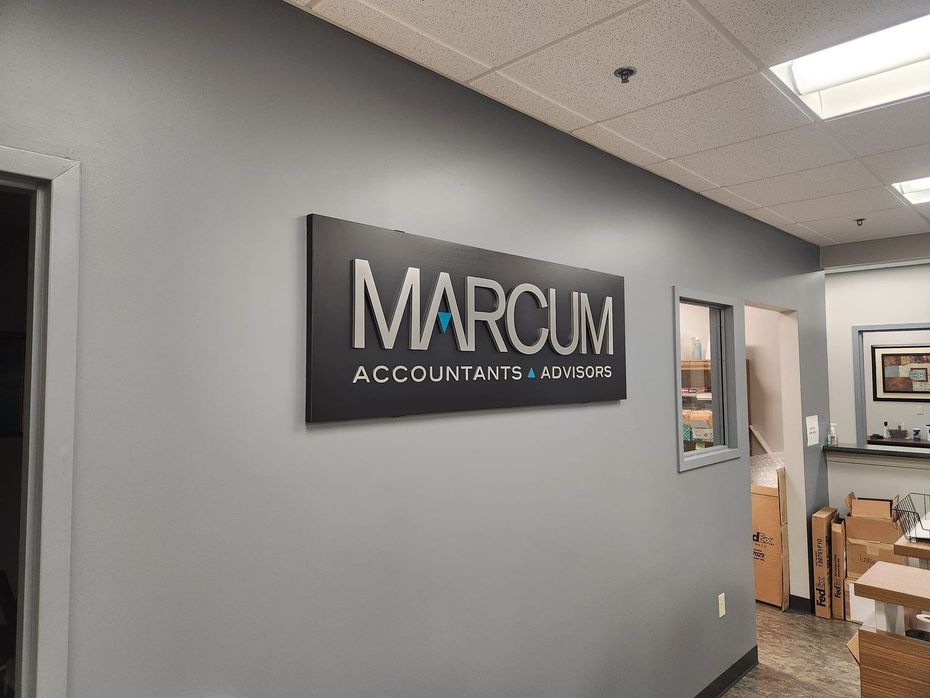 Marcum sign on a gray office wall; 
