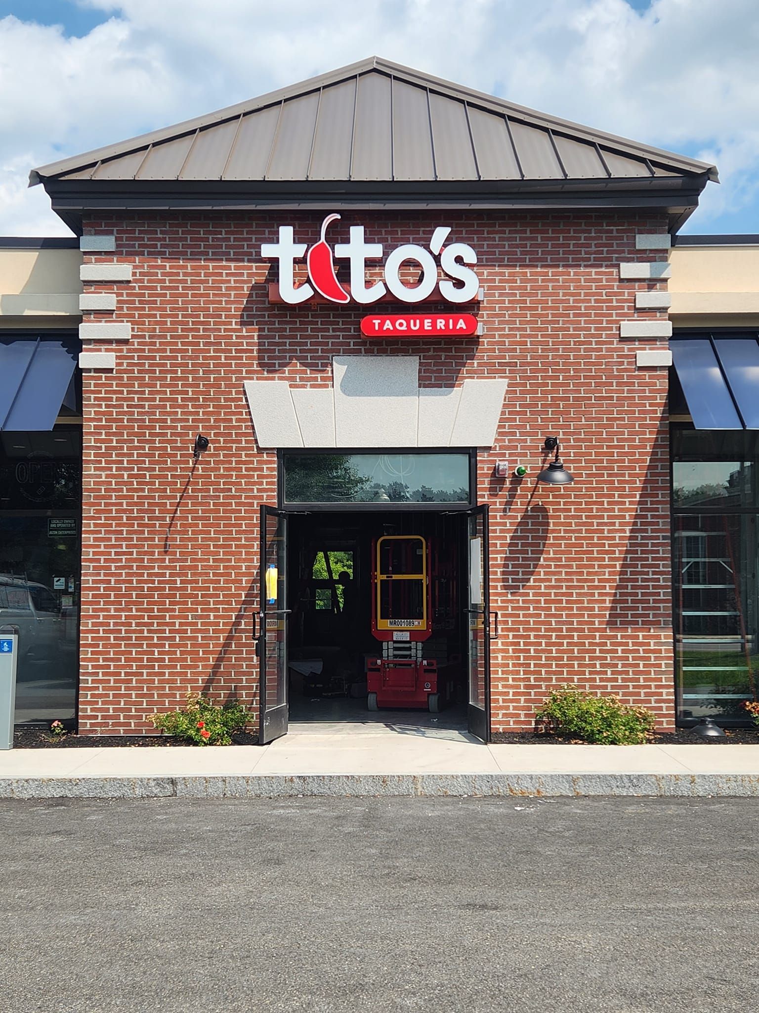 Tito's Restaurant entrance with red brick facade and sign, open door, construction lift visible inside.