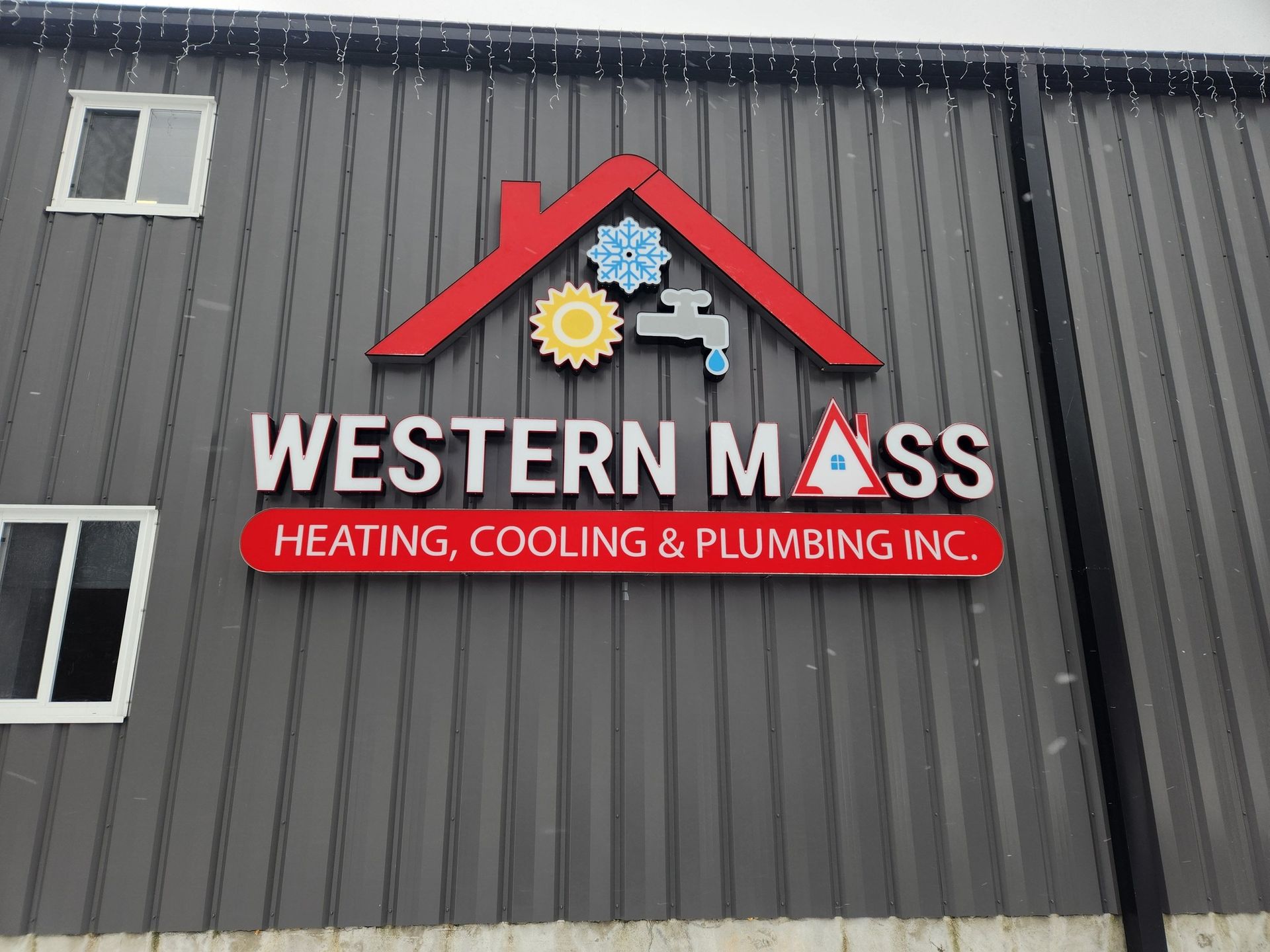  Red house outline with gear, snowflake, faucet icons above text on metal building.
