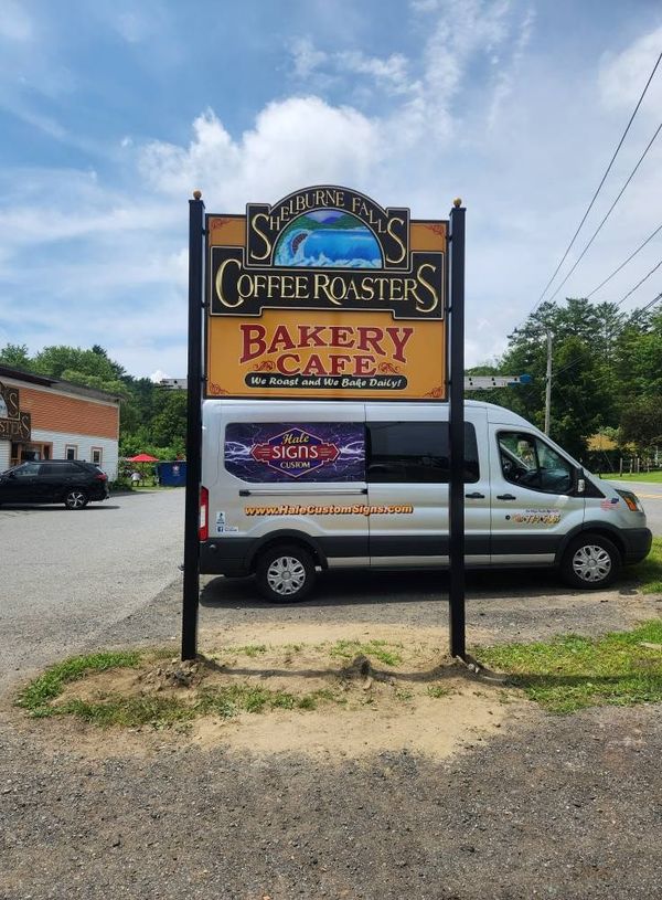 Sign for Summit's Coffee Roasters bakery cafe with a van parked in front of it on a sunny day.