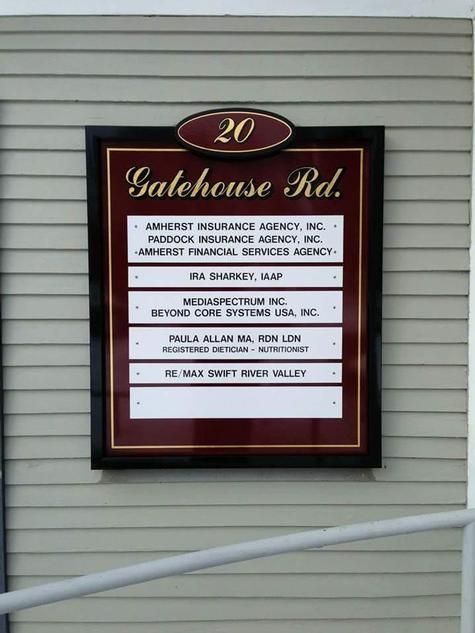 Sign for businesses at 20 Gatehouse Rd. with names and addresses listed on a framed board, black and burgundy.