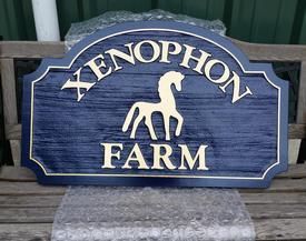 Blue and gold Xenophon Farm sign with a horse silhouette.