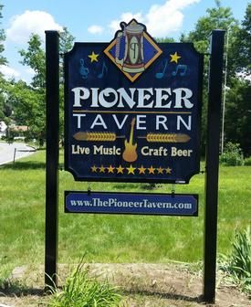 Sign for Pioneer Tavern: blue and gold, black posts, live music, craft beer.