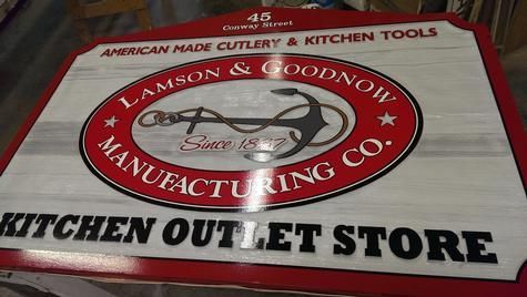 Sign for Lamson & Goodnow Manufacturing Co. Kitchen Outlet Store: red and white with logo and text.