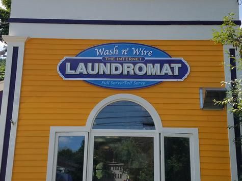 Yellow laundromat building with blue and white sign that reads 