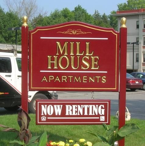 Sign for Mill House Apartments, red with gold lettering, saying 