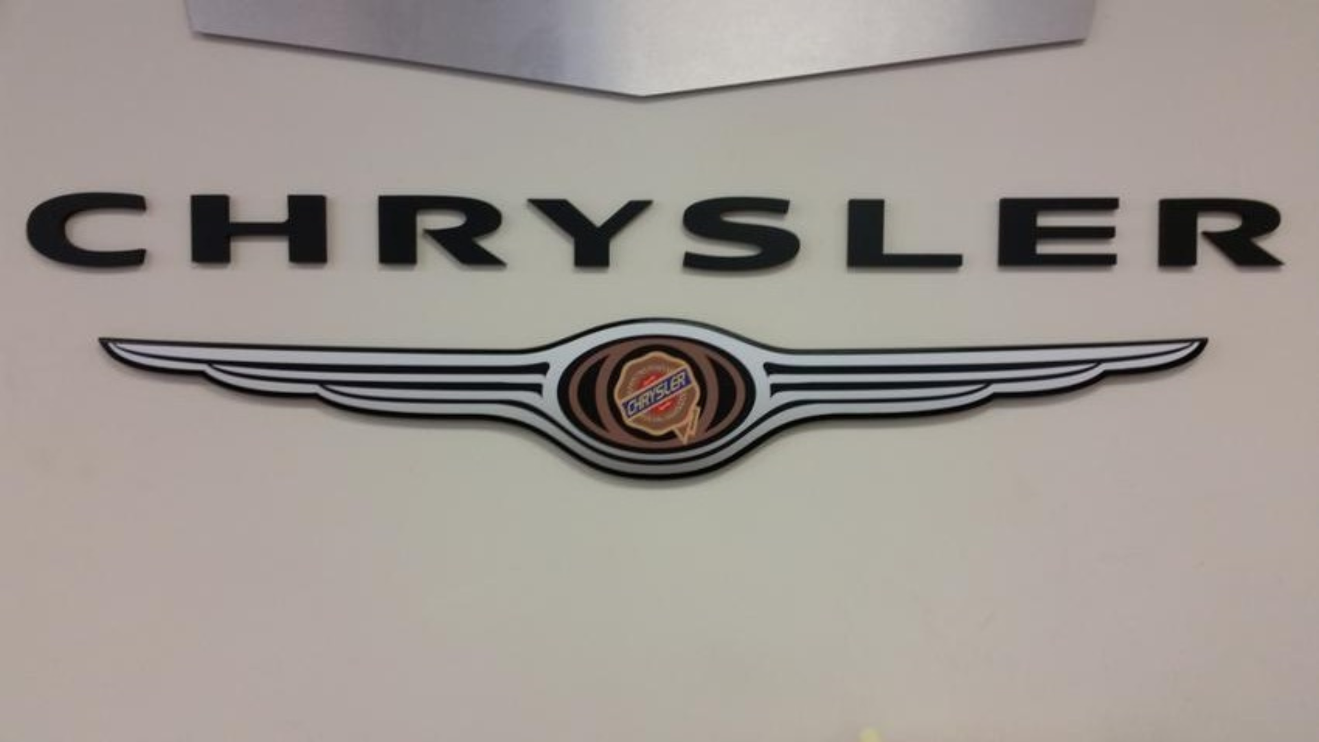 Chrysler logo and wordmark, black text on beige background, with winged emblem.