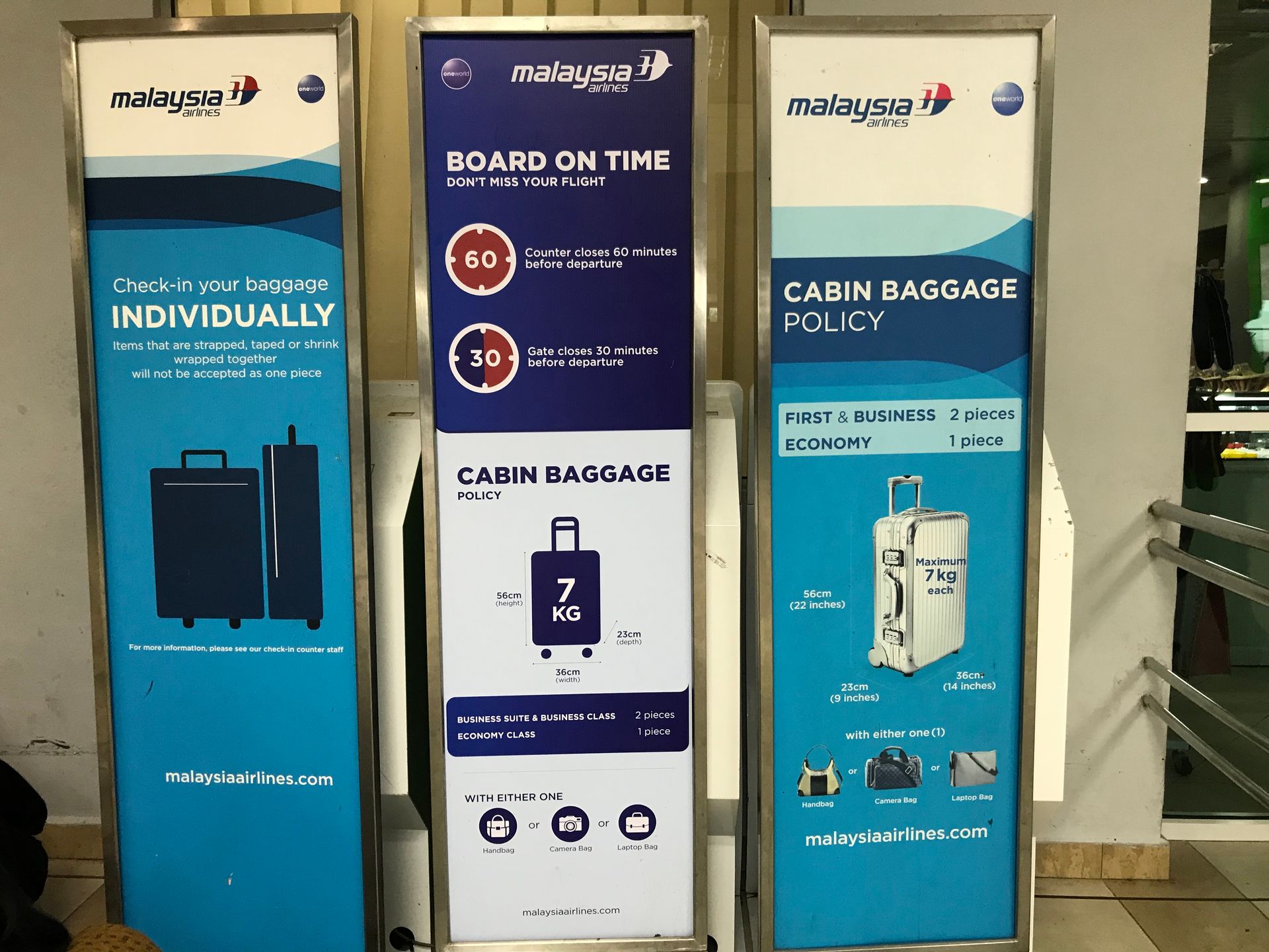 Three Malaysia Airlines signs: baggage check, on-time boarding, cabin baggage policy; blue, white.