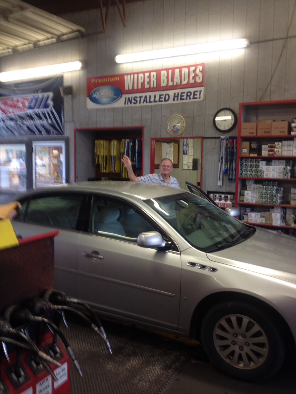 A man is standing next to a silver car in a garage.