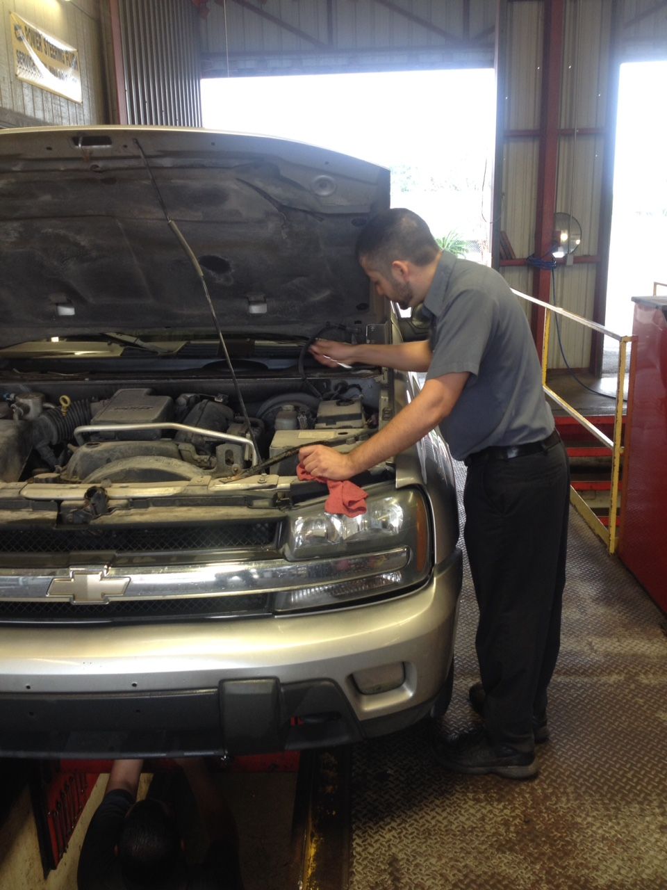 A man is working on the engine of a car in a garage.