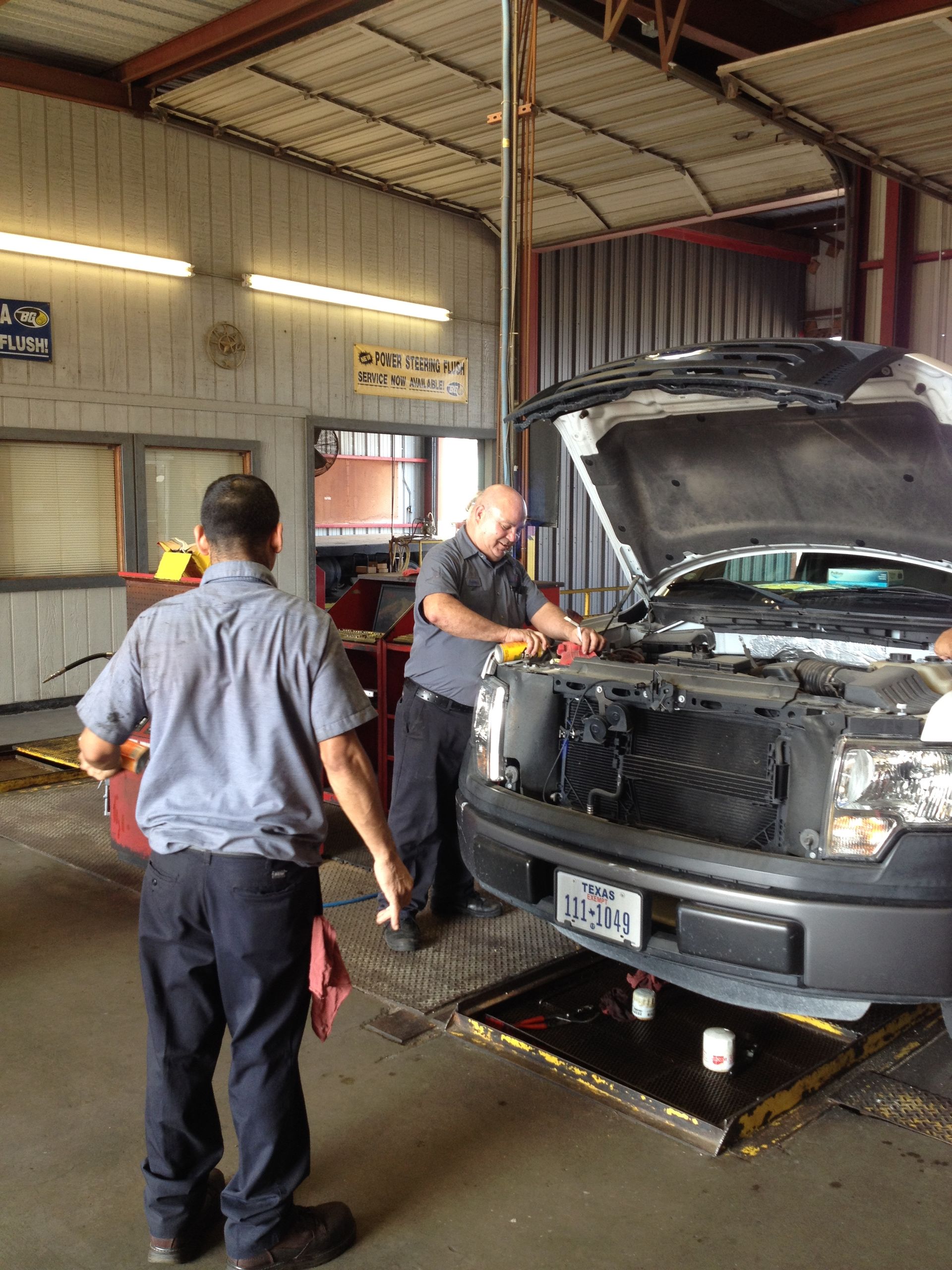 Two men are working on a car in a garage.