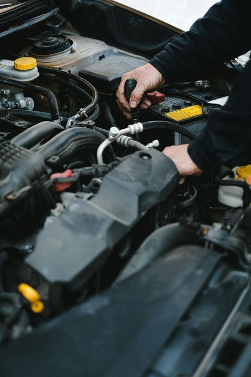 A man is working on the engine of a car with a screwdriver.
