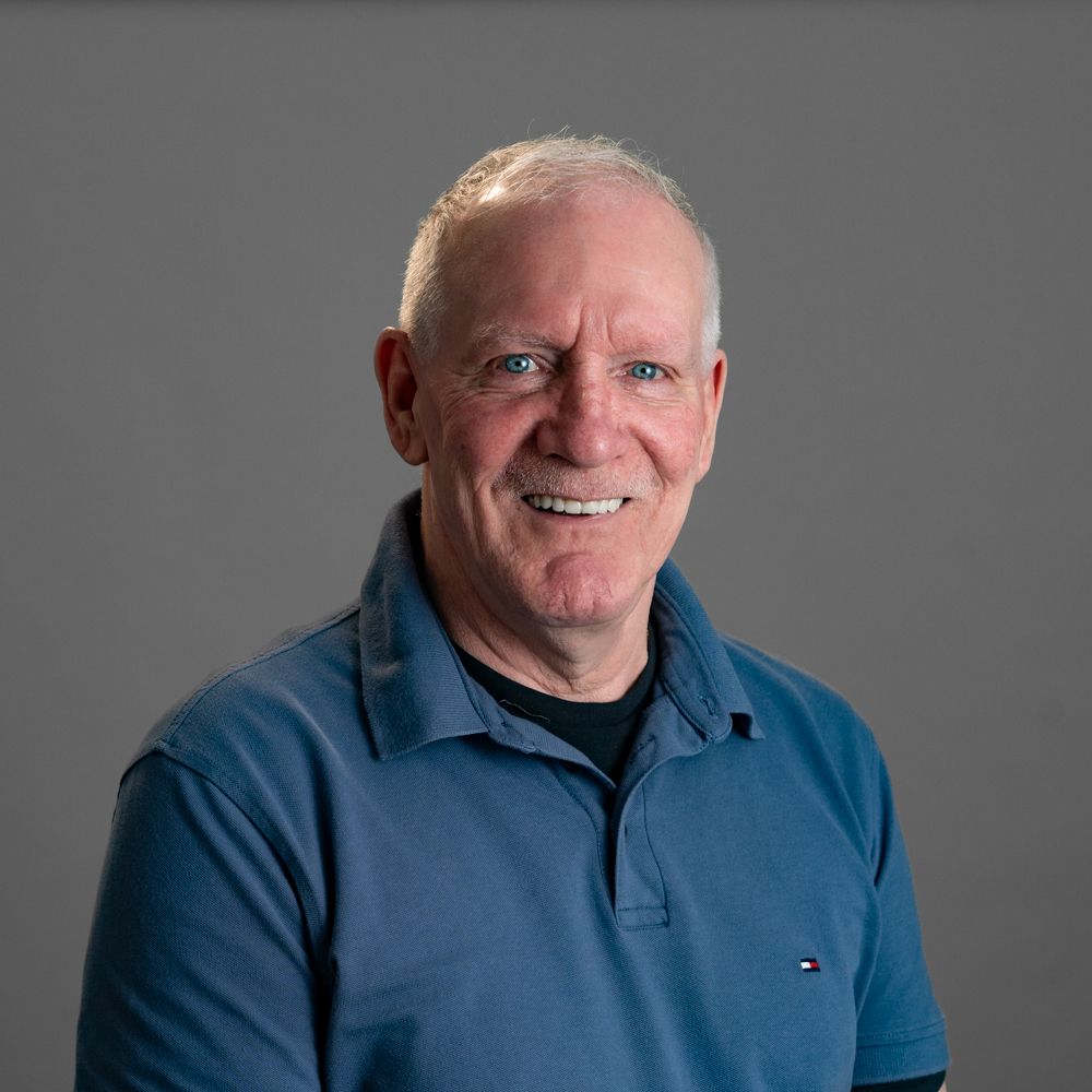 A man wearing a blue polo shirt is smiling for the camera.