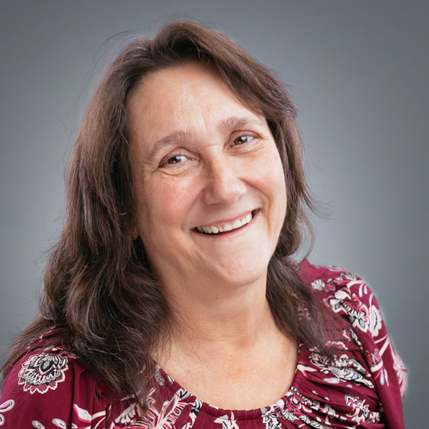 A woman in a red shirt is smiling for the camera.