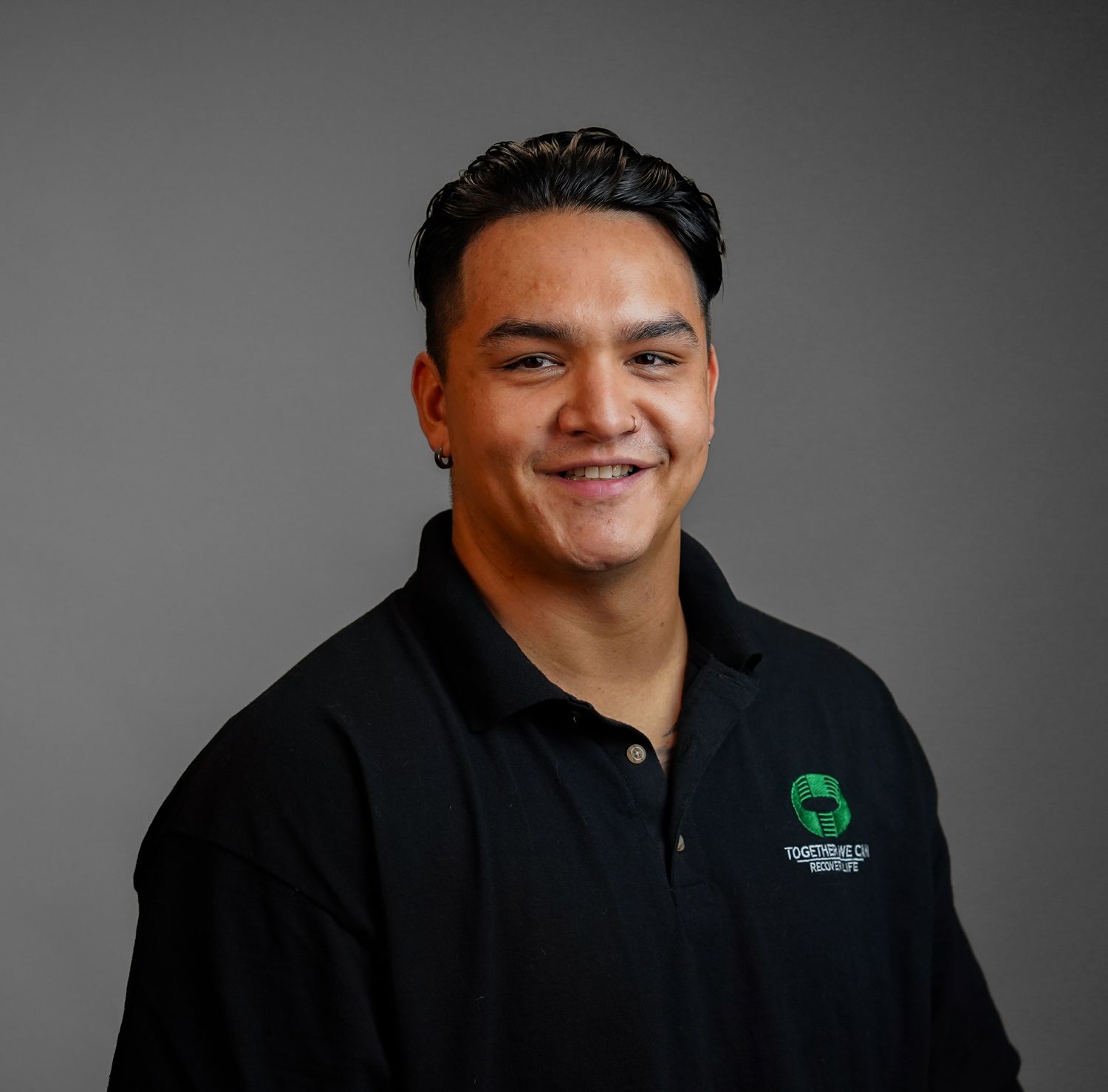 A man wearing a black shirt with a green logo on it