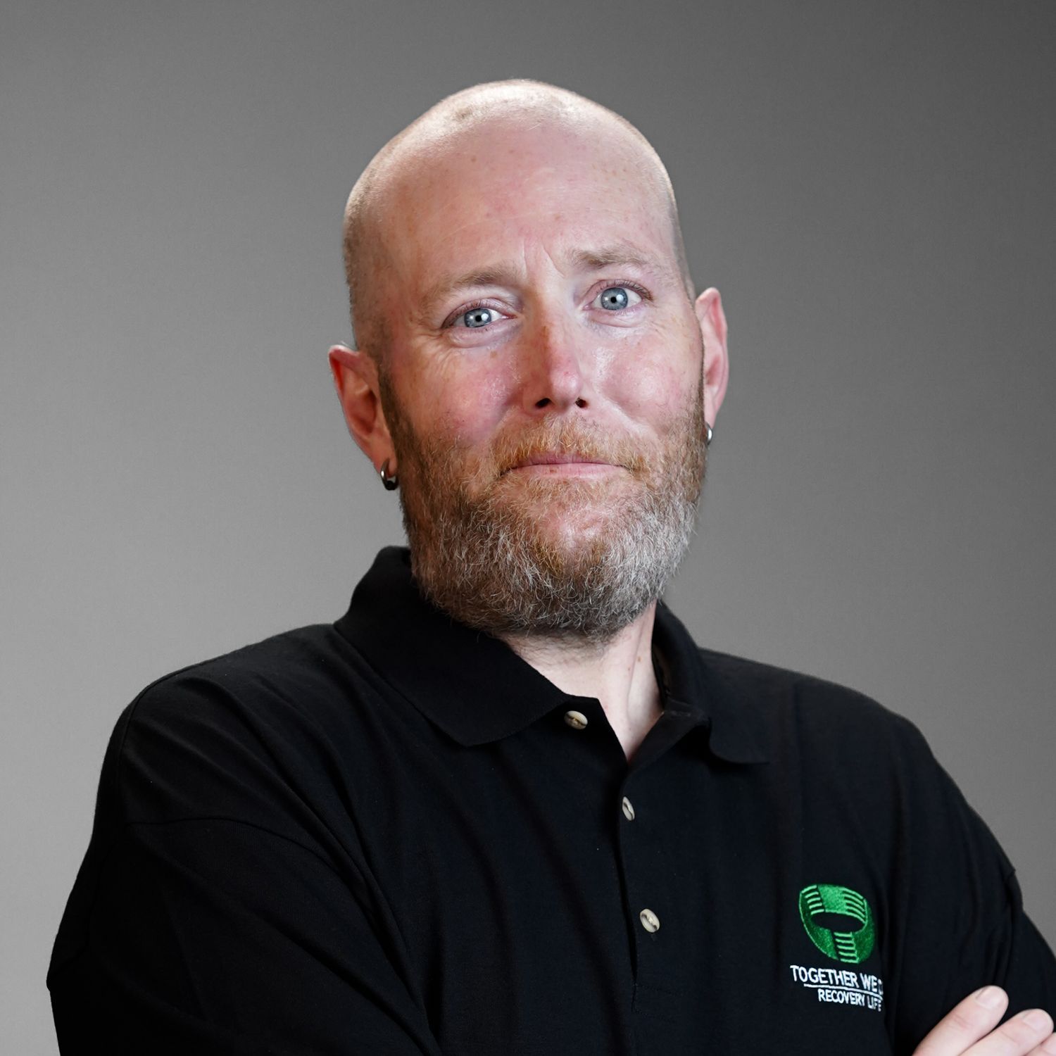 A bald man with a beard wearing a black polo shirt