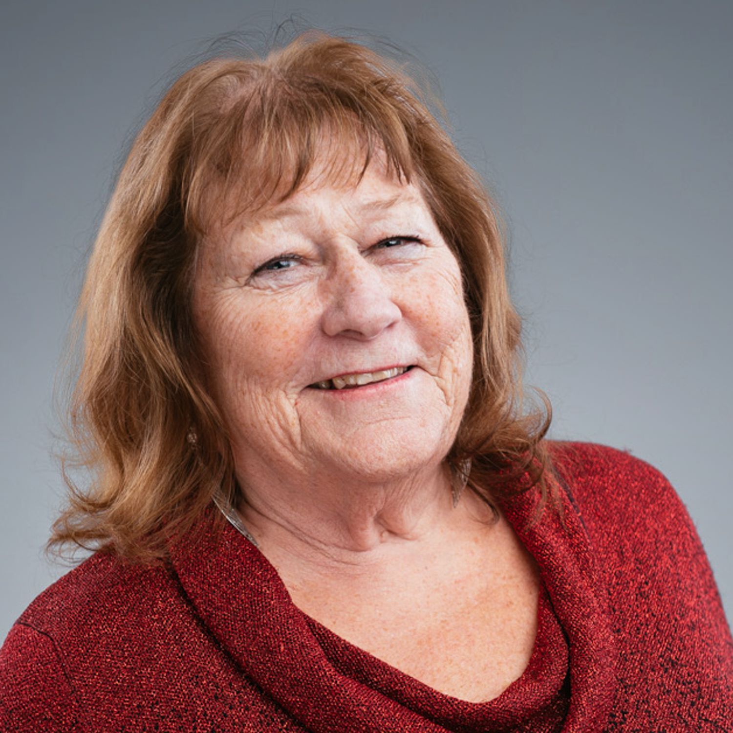 A woman in a red sweater is smiling for the camera.