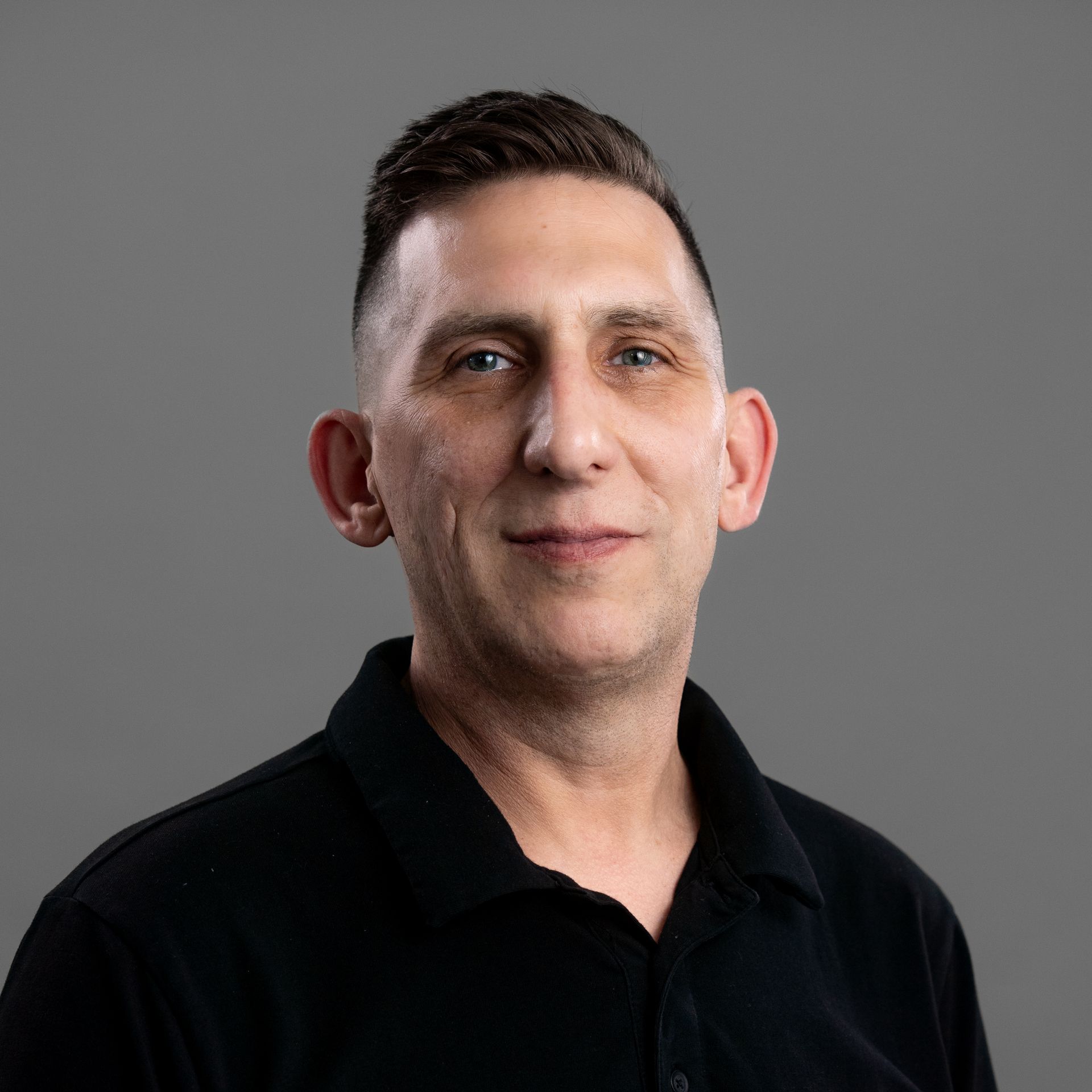 A man with a tattoo on his arm is wearing a white t-shirt.