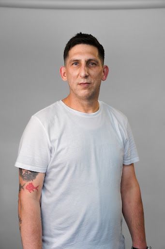 A man with a tattoo on his arm is wearing a white t-shirt.