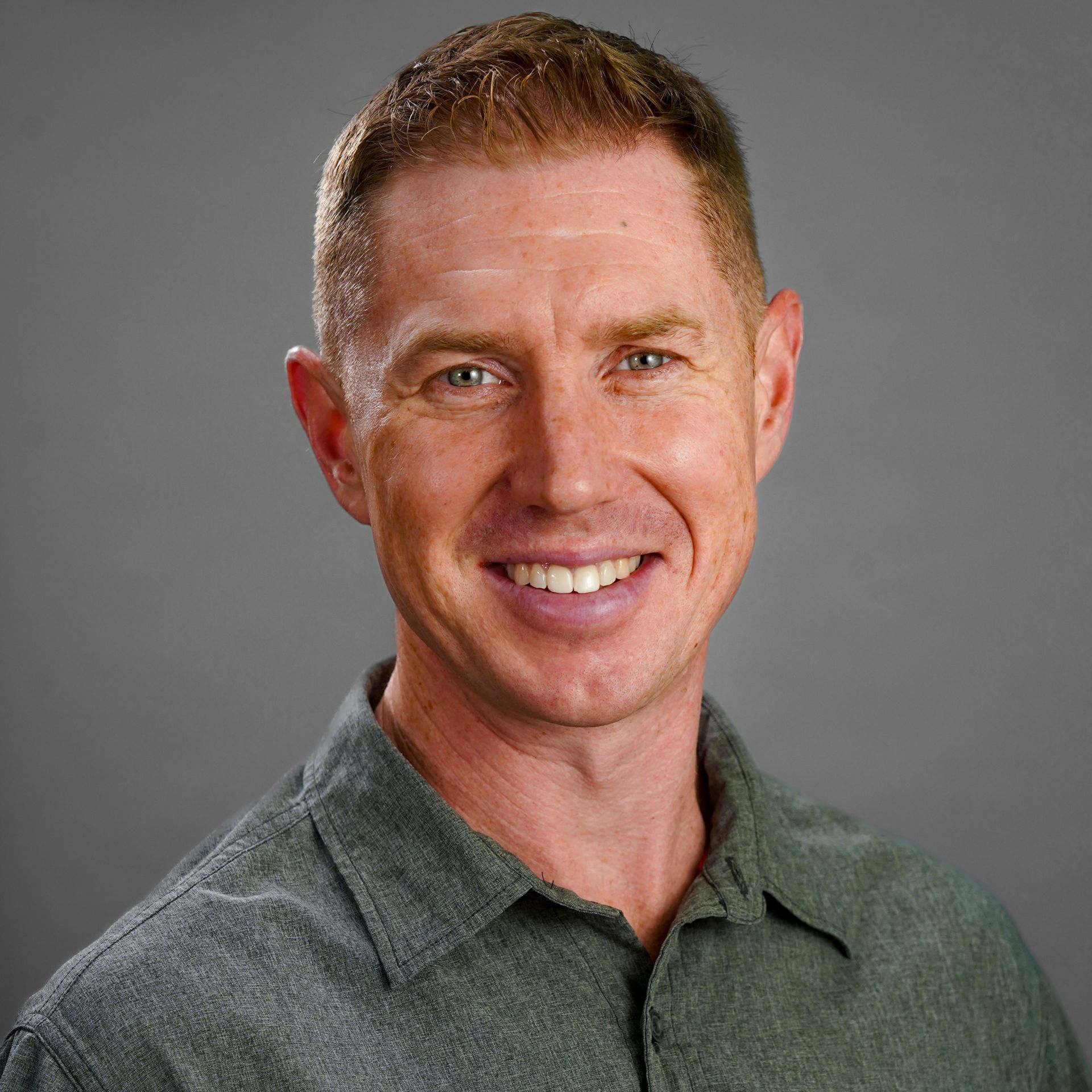 A man in a green shirt is smiling for the camera.