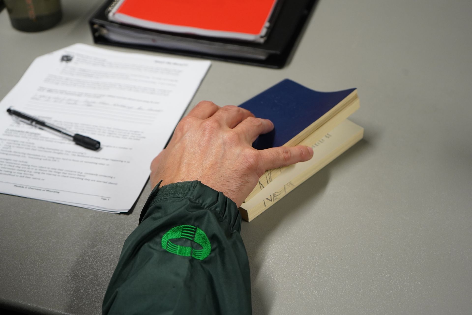 A person wearing a green jacket is holding a book