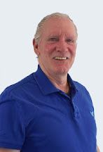 A man wearing a blue polo shirt is smiling for the camera.