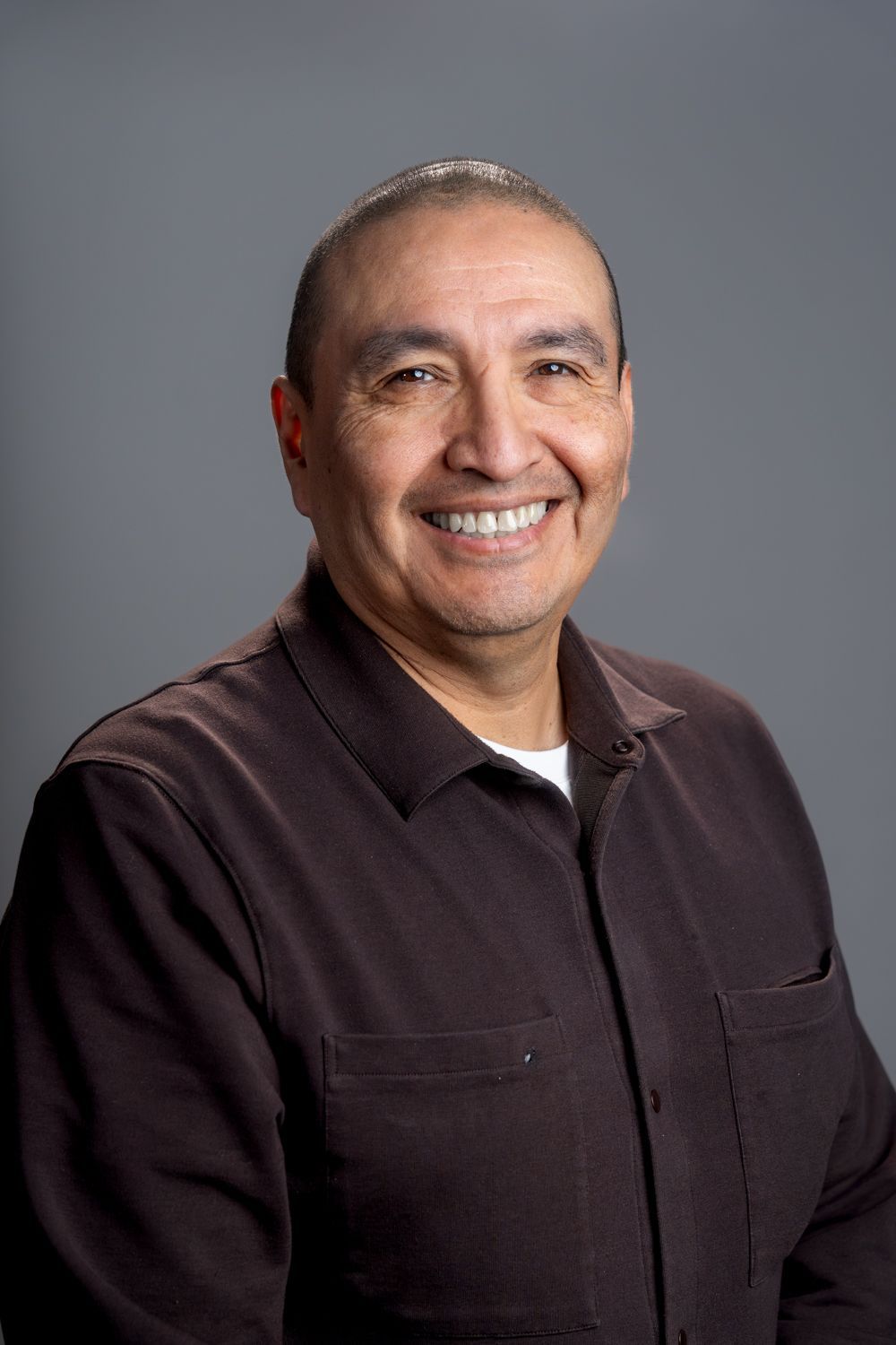 A man wearing a black polo shirt is smiling for the camera.