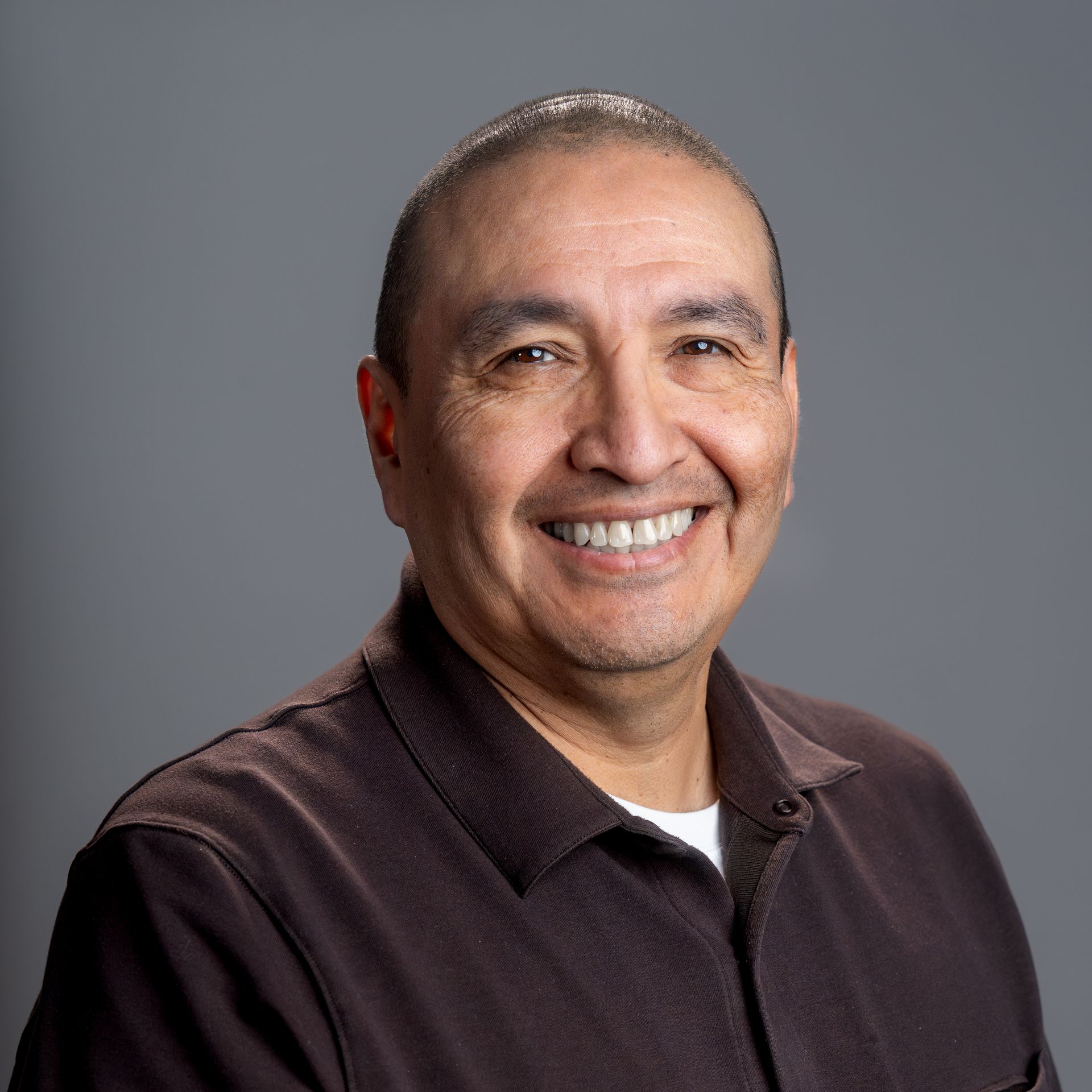 A man wearing a black polo shirt is smiling for the camera.