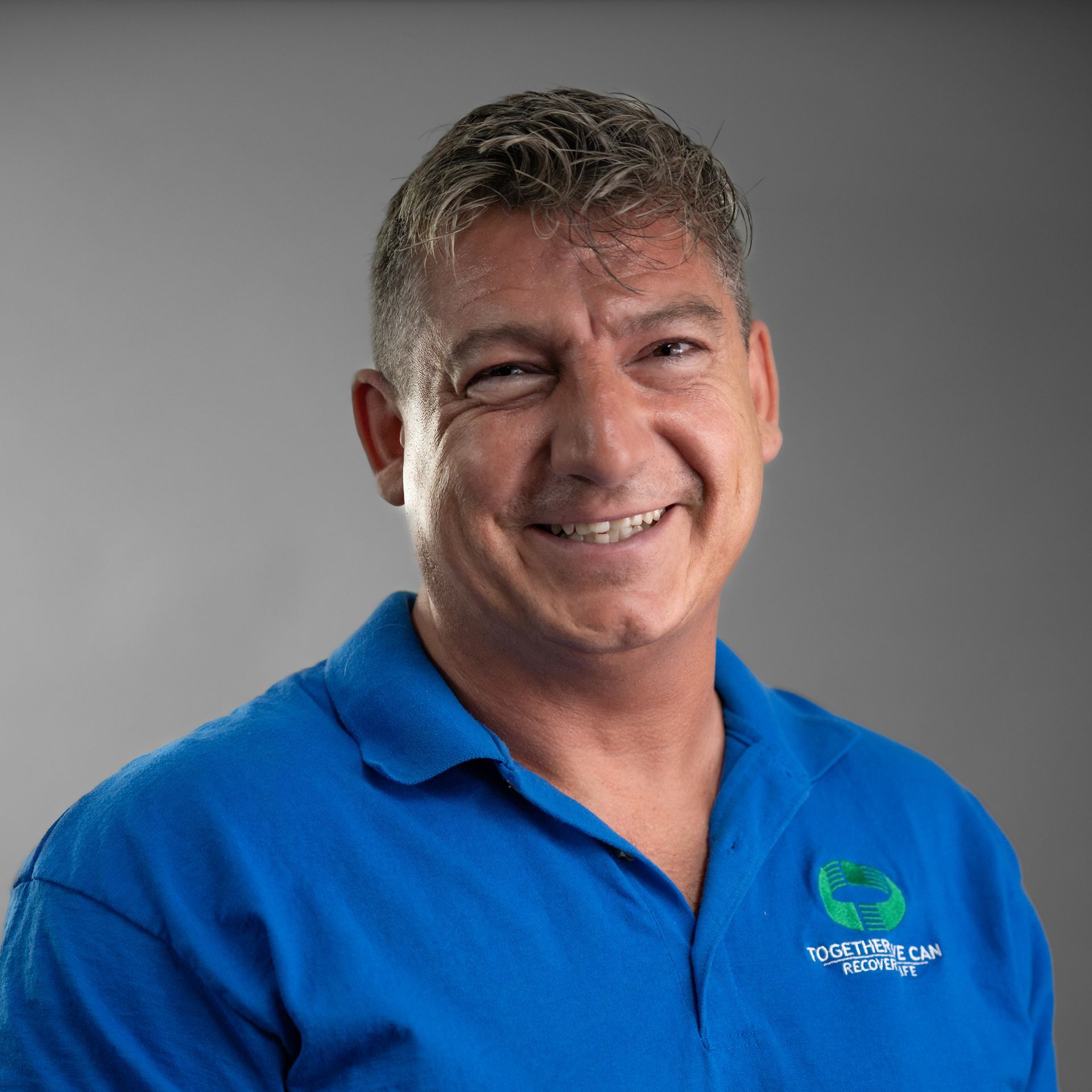 A man in a blue shirt is smiling for the camera.