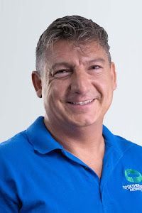 A man in a blue shirt is smiling for the camera.