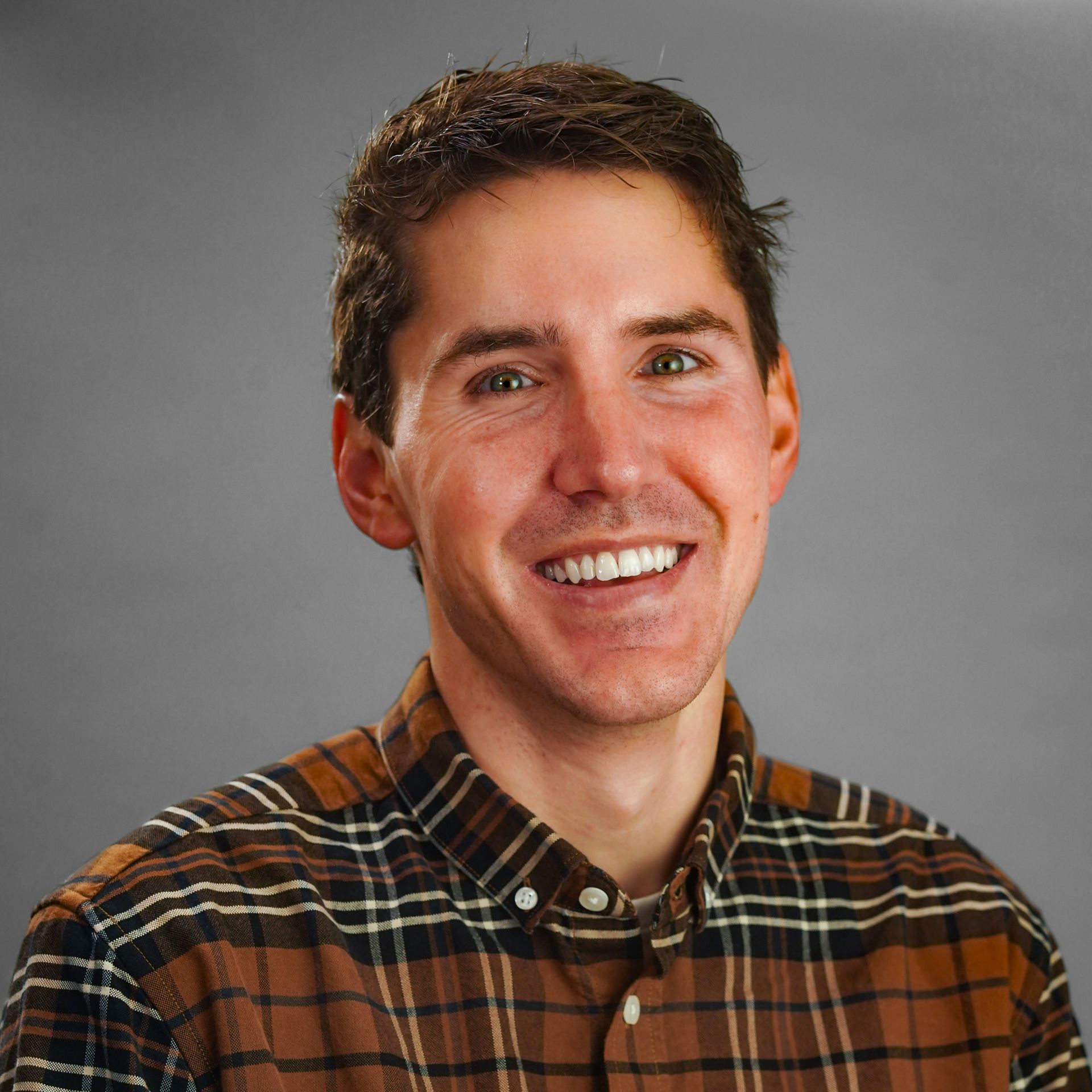 A man in a plaid shirt is smiling for the camera.