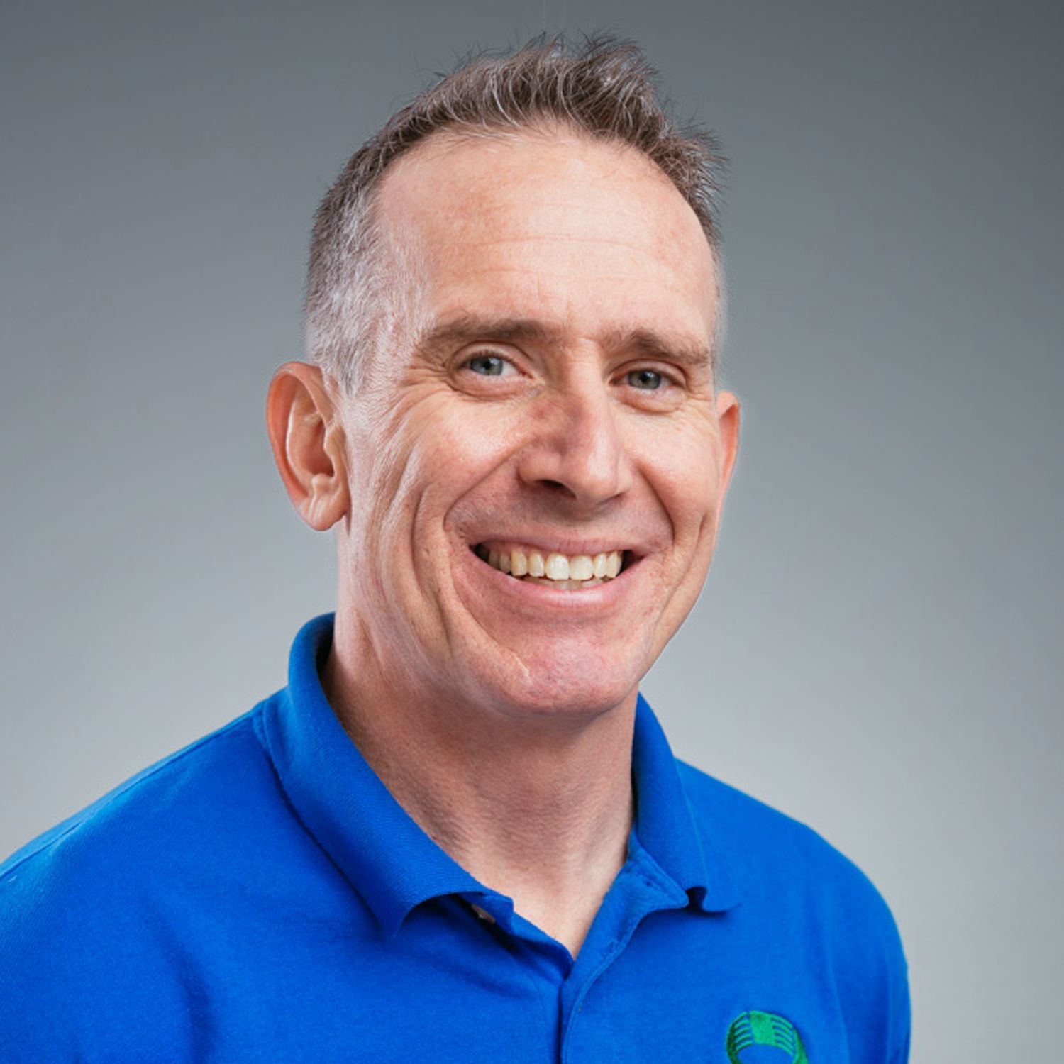 A man in a blue shirt is smiling for the camera.
