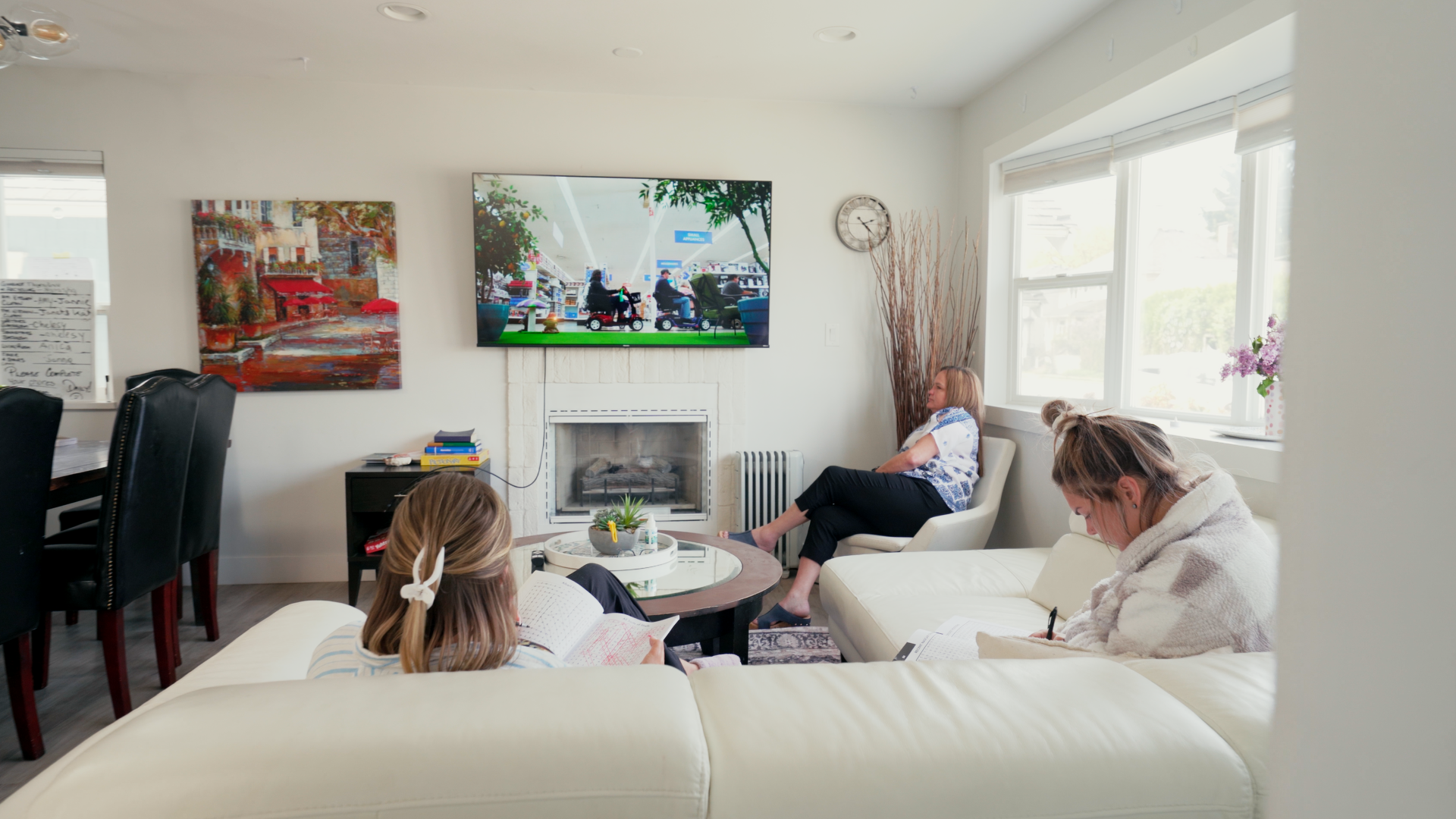A family is sitting on a couch in a living room watching a television.