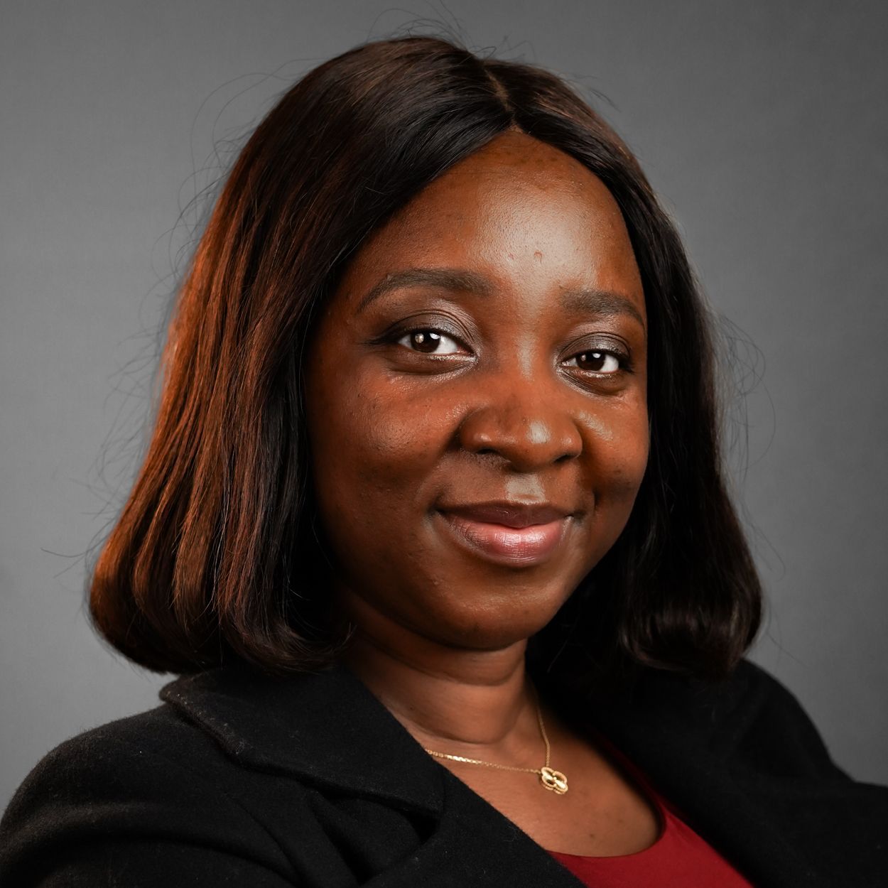 A woman wearing a black jacket and a red shirt is smiling for the camera.