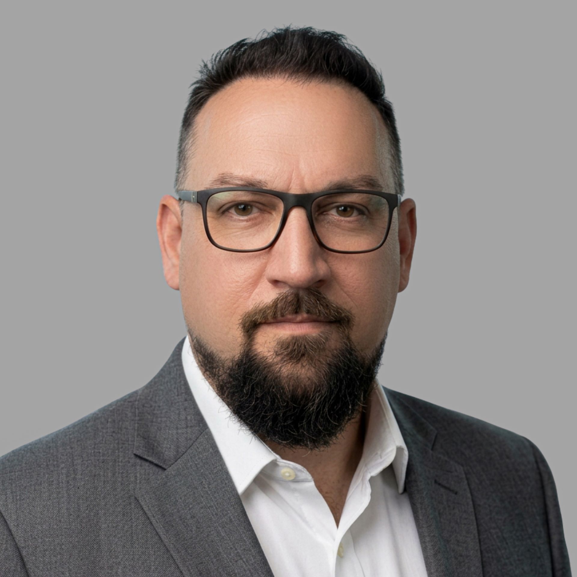 A man with a beard wearing glasses and a white shirt