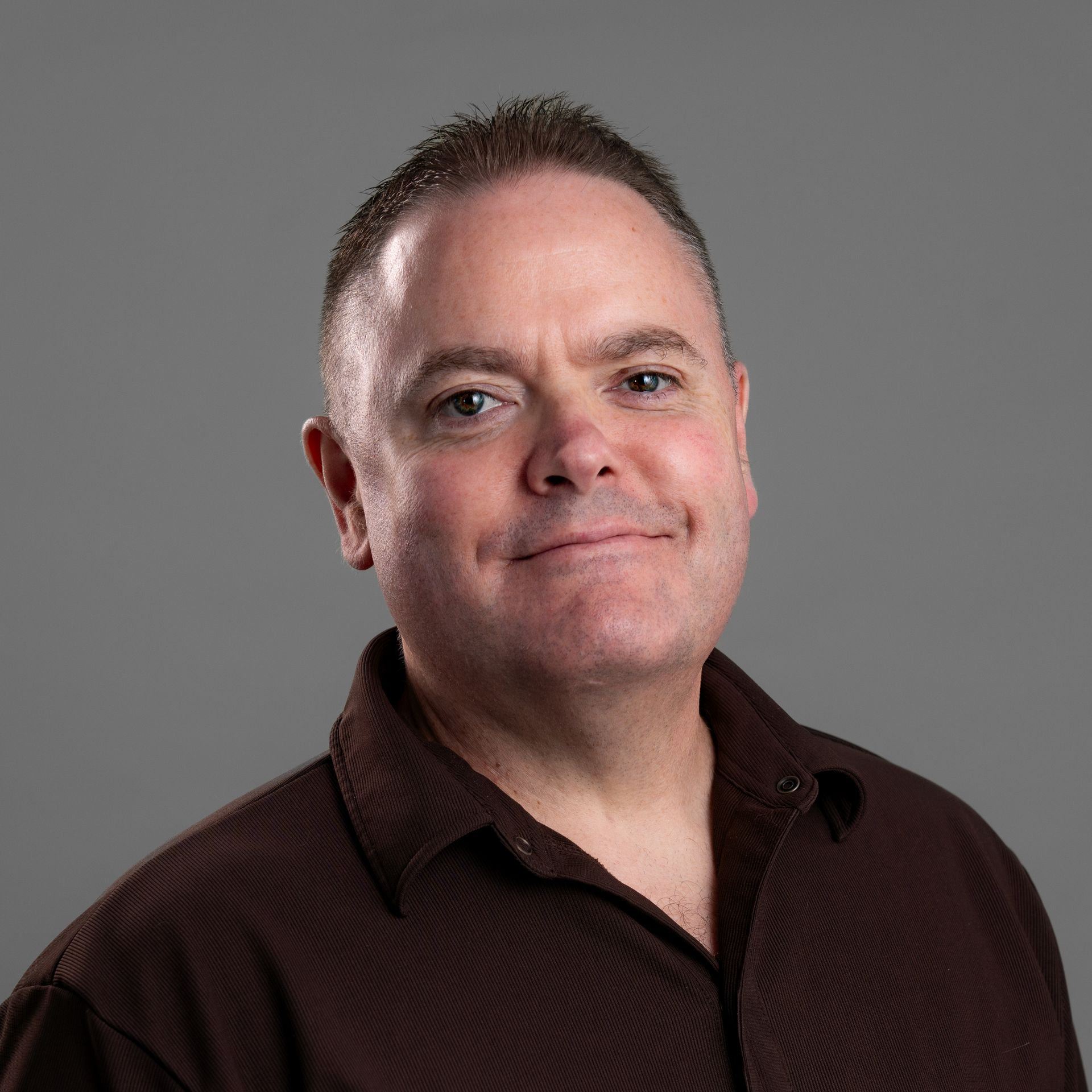 A man in a black and white shirt is smiling for the camera.