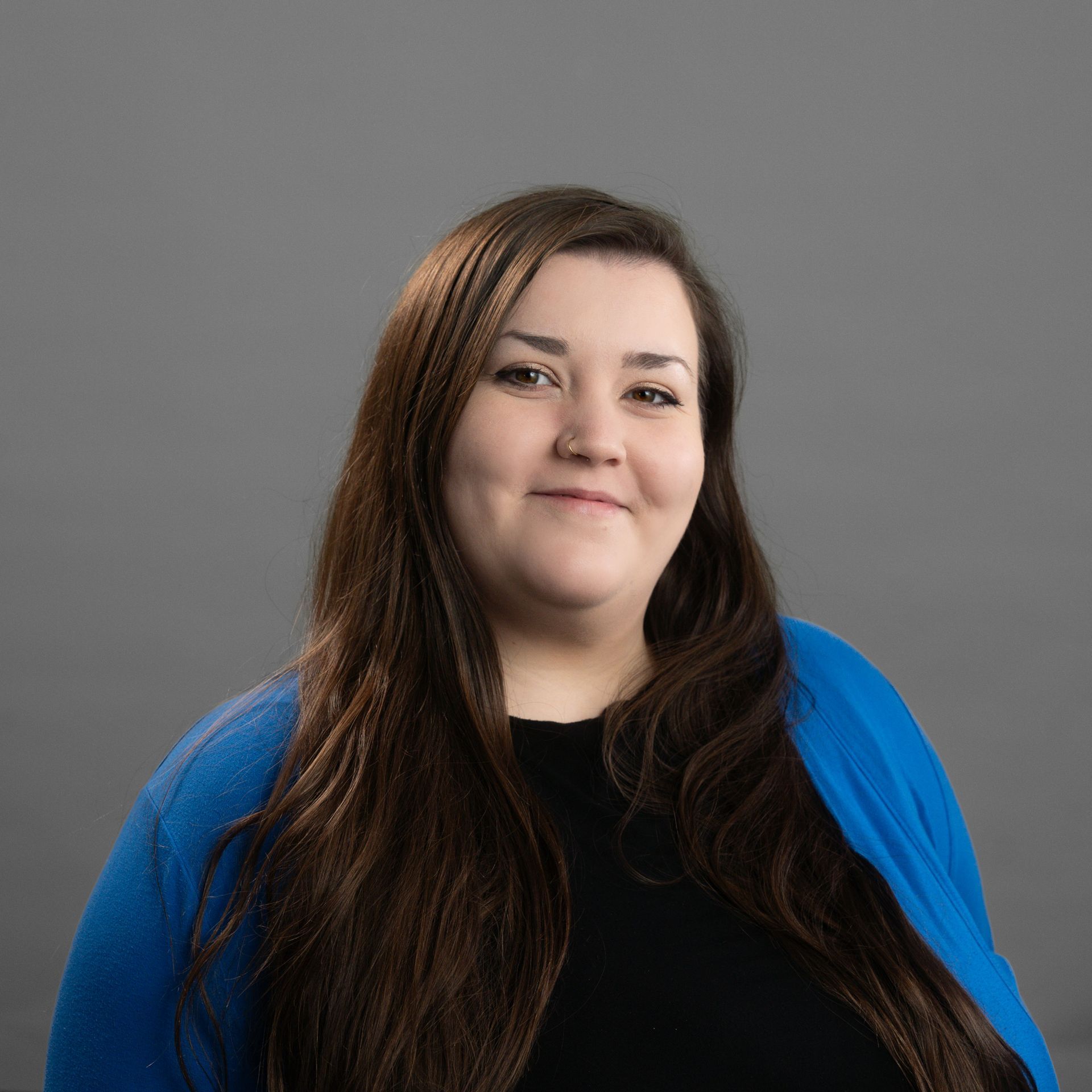 A woman with long hair is wearing a blue sweater and a black shirt.