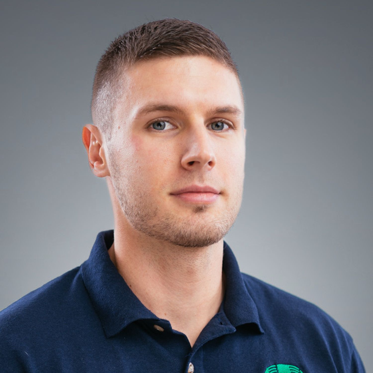 A man wearing a blue shirt with a green logo on it