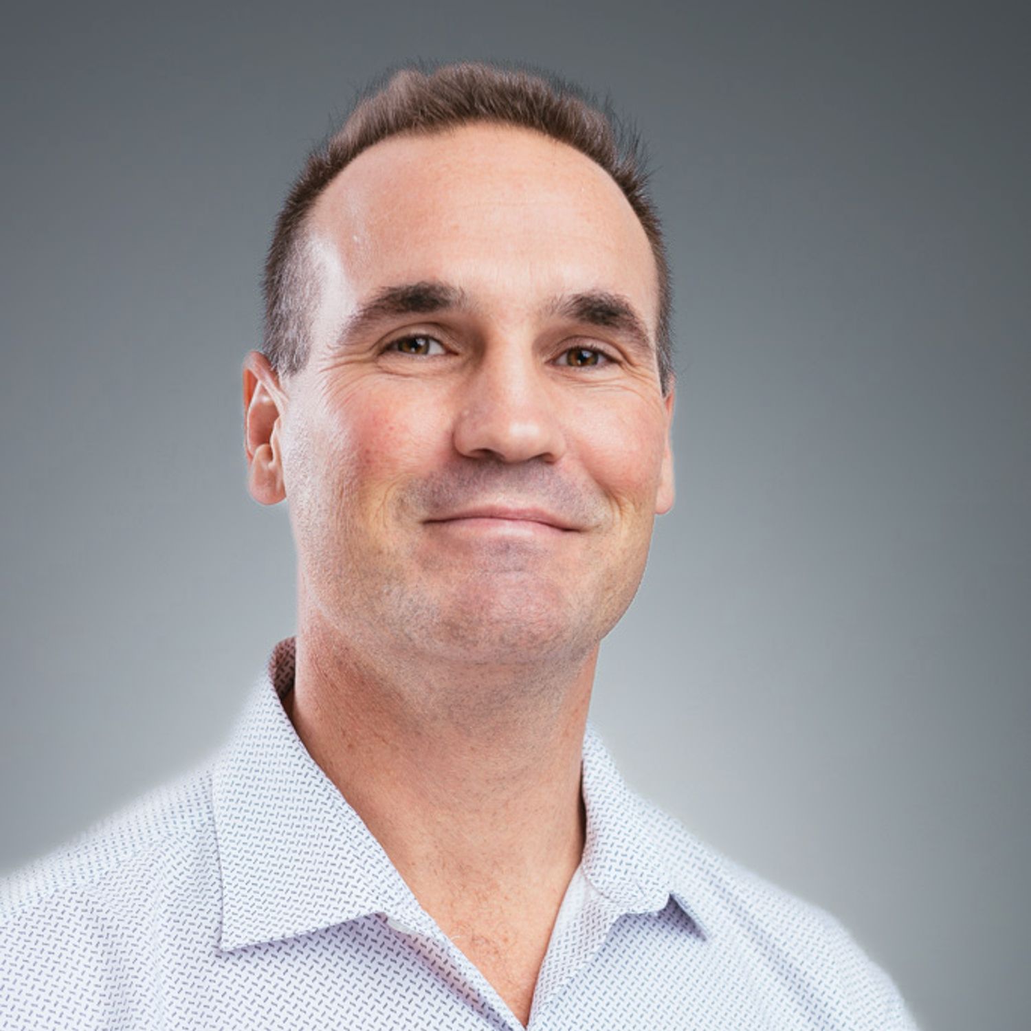A man in a white shirt is smiling for the camera.