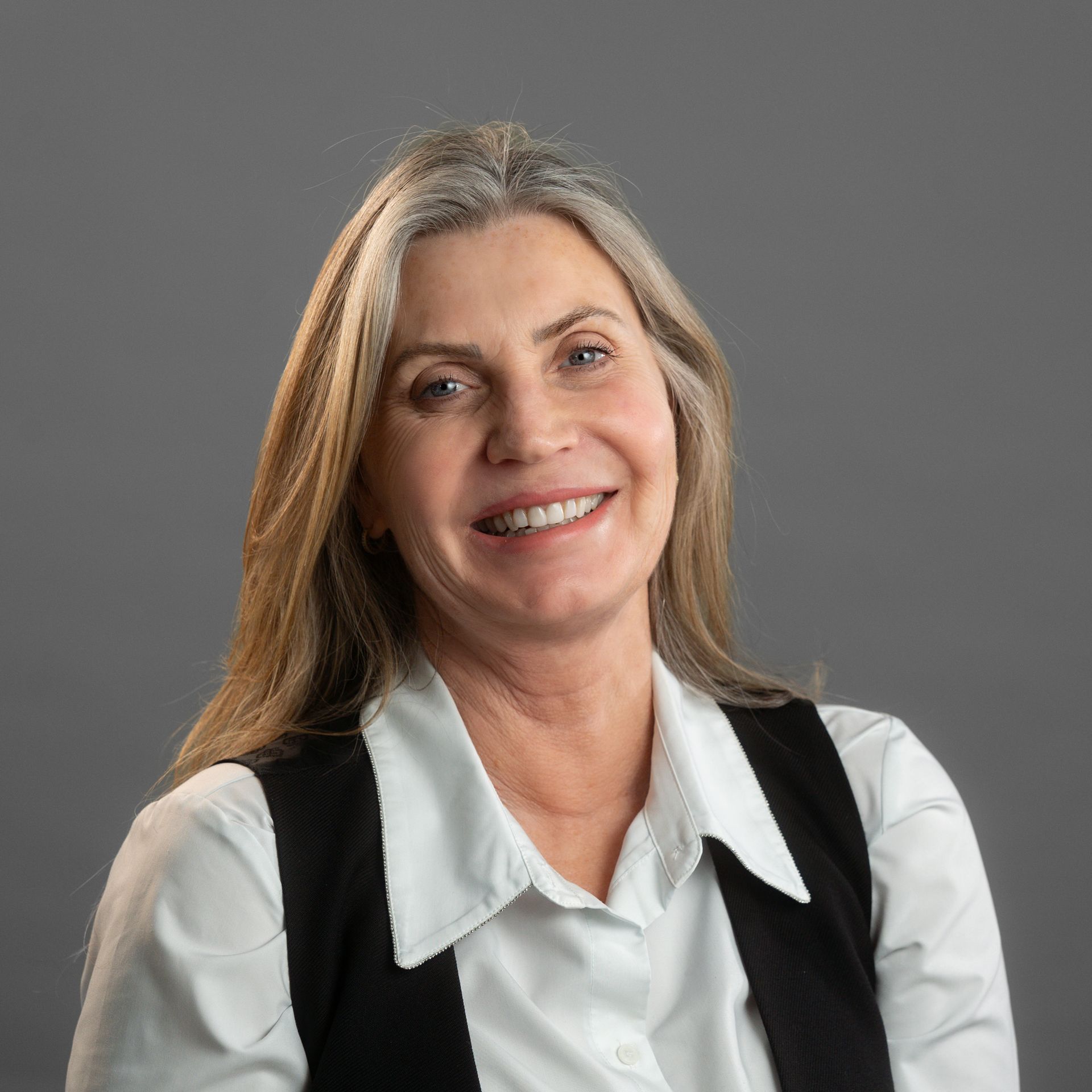 A woman with long blonde hair is smiling and wearing a black jacket.