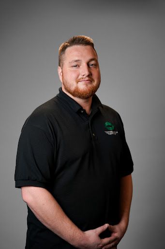 A man with a beard is wearing a black shirt and posing for a picture.