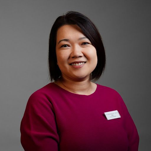 A woman in a purple shirt is smiling for the camera.