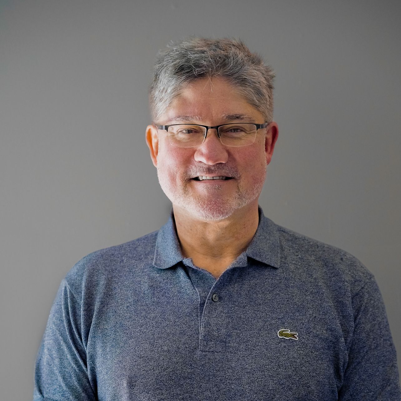 A man with a beard and glasses is wearing a blue polo shirt.