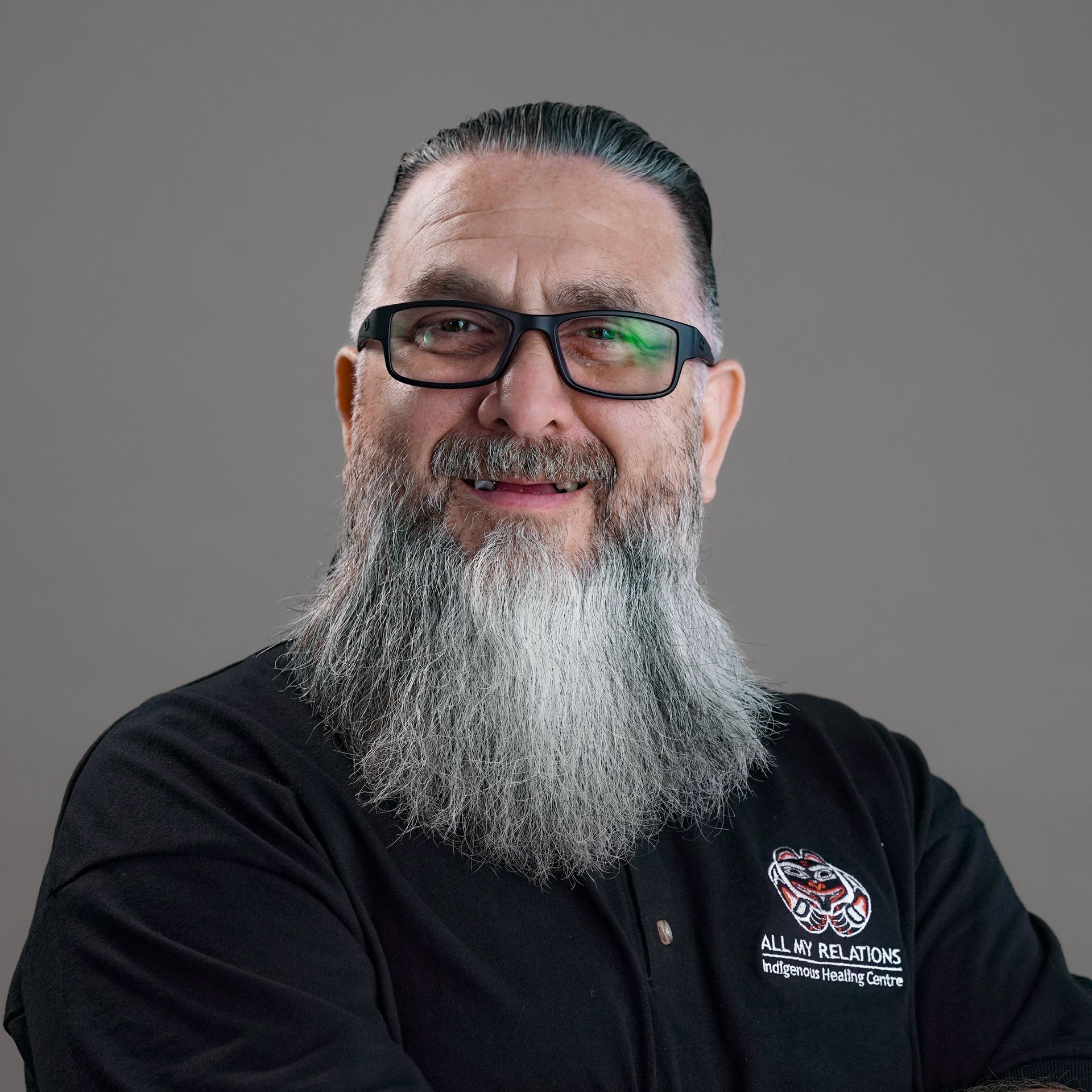 A man with a beard and glasses is wearing a colorful shirt.