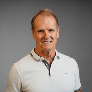 A man in a white polo shirt is smiling for the camera.