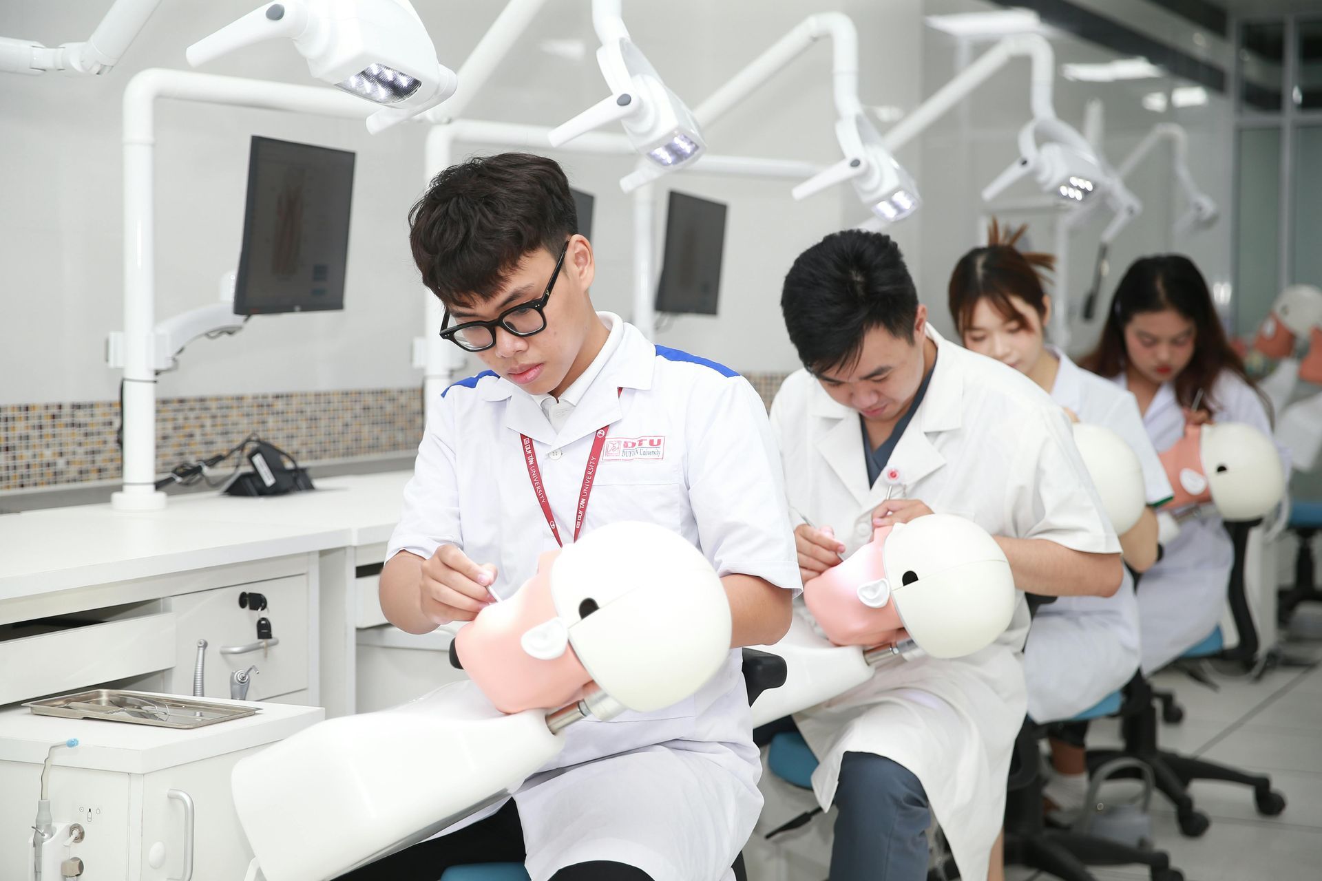 A group of dentists are working on a mannequin in a dental lab.