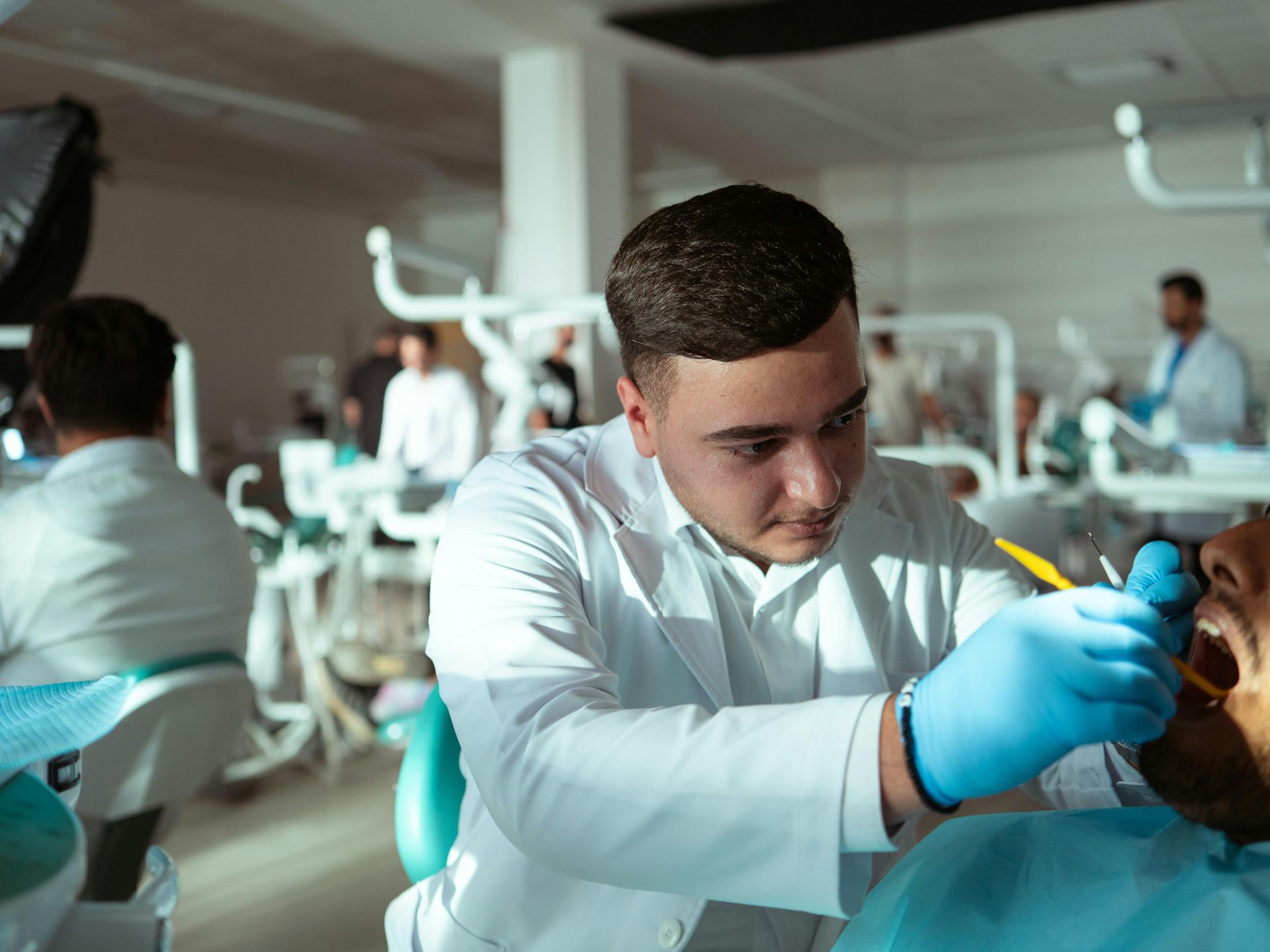Dentist examining a patient's mouth with tools in a dental office.