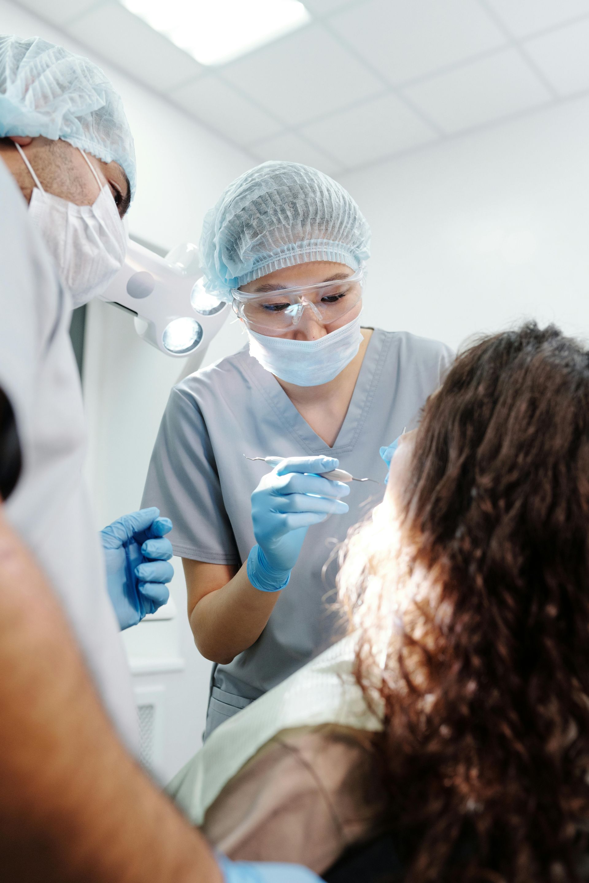 Dentists examining a patient's mouth; bright dental office setting.
